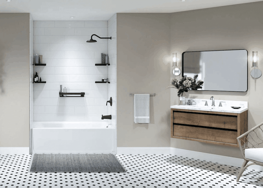Modern bathroom with white subway tile shower, black fixtures, wooden vanity with white countertop, rounded mirror, and black and white mosaic tile flooring