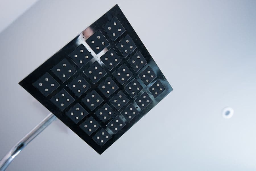 Black waffle grid of 25 connected microdots or electrode contacts arranged in a 5x5 pattern on a thin stem, viewed from above against a white background