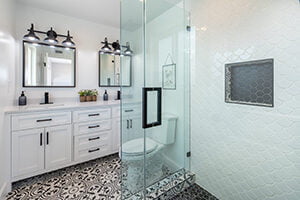 Bathroom Remodel Costs Springfield MO A remodeled bathroom with white cabinetry, black and white patterned tile, and a glass shower