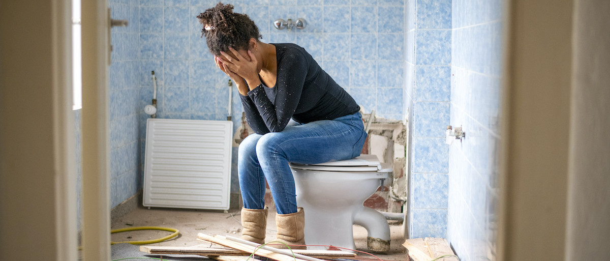 woman sitting in a demo'd bathroom frustrated that it is taking so long.